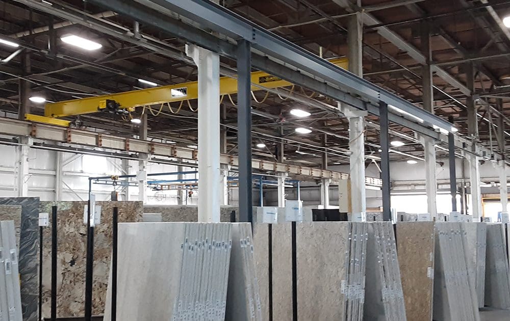 A CraneWerks overhead bridge crane installed in a stone, marble, and granite showroom
